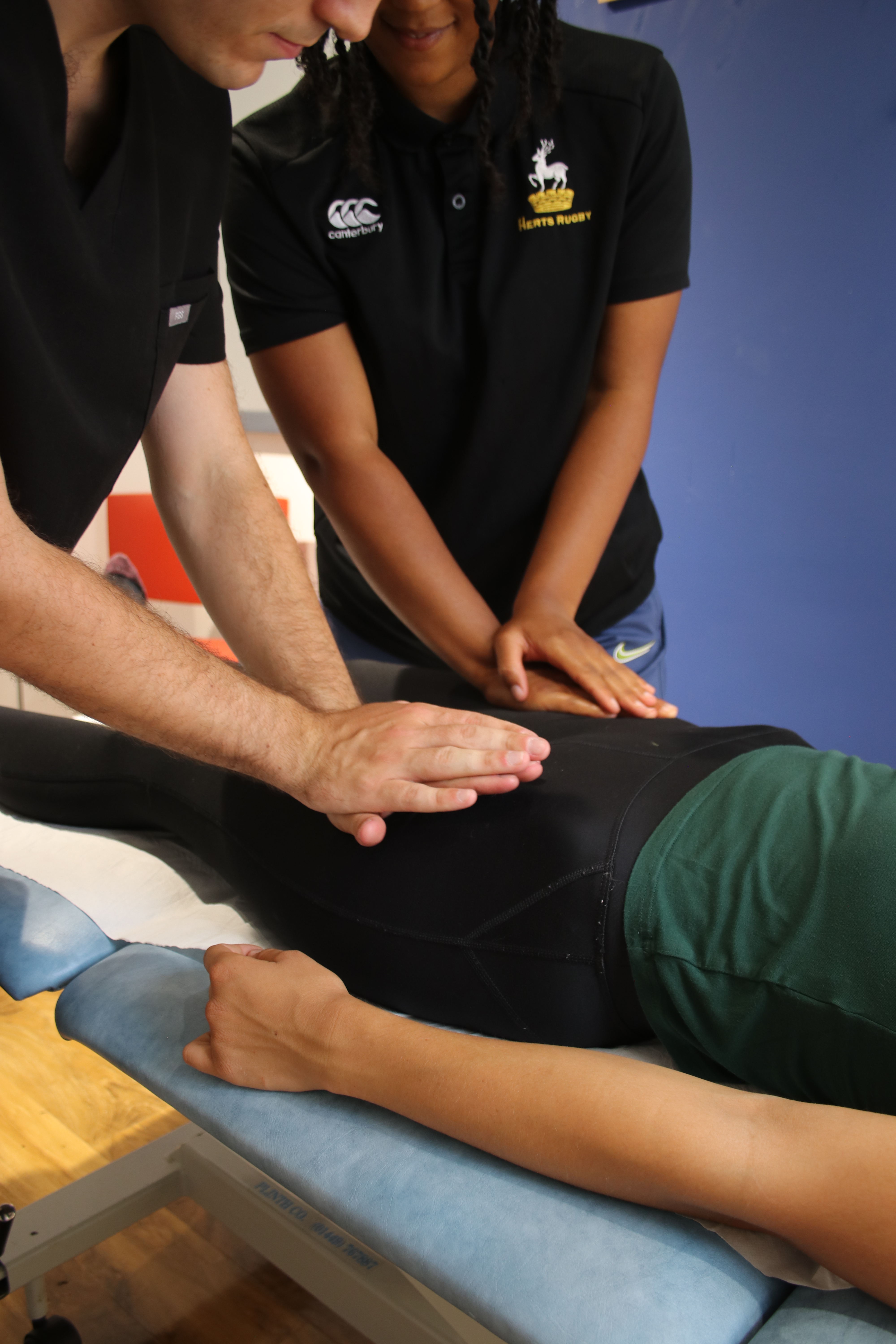 Osteopath showing client how to massage a patients thighs